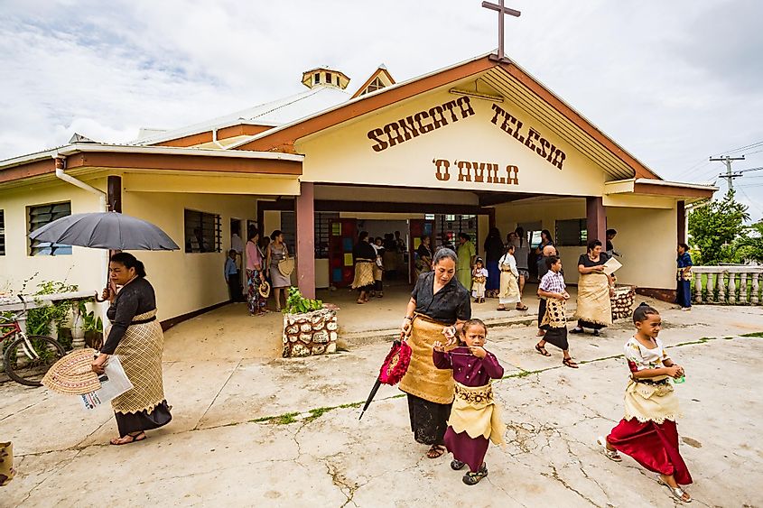  Polynesian parishioners in traditional Tongan dress walk out of church Sangata Teleisia 'o 'Avila as Catholic Mass ends, Pangai village, Ha'apai Group in Tonga, Polynesia, via maloff / Shutterstock.com