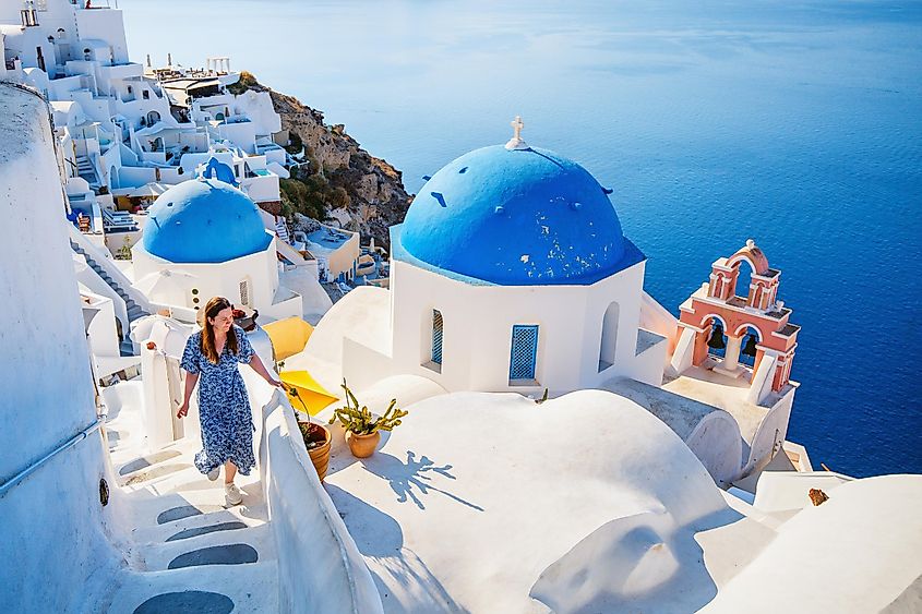 A woman enjoying view of blue-domed church in Oia village on Santorini island Greece. Image used under license from Shutterstock.com.
